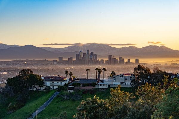 Photo of Los Angeles with houses and palm trees in the foreground and mountains in the background. By Juan Carlos Becerra on Unsplash.
