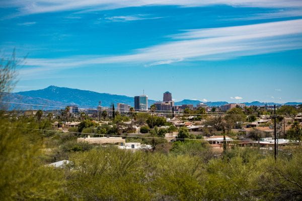 Photo of Tucson with shrubs in the foreground and mountains in the background. By Manny Pacheco on Unsplash.